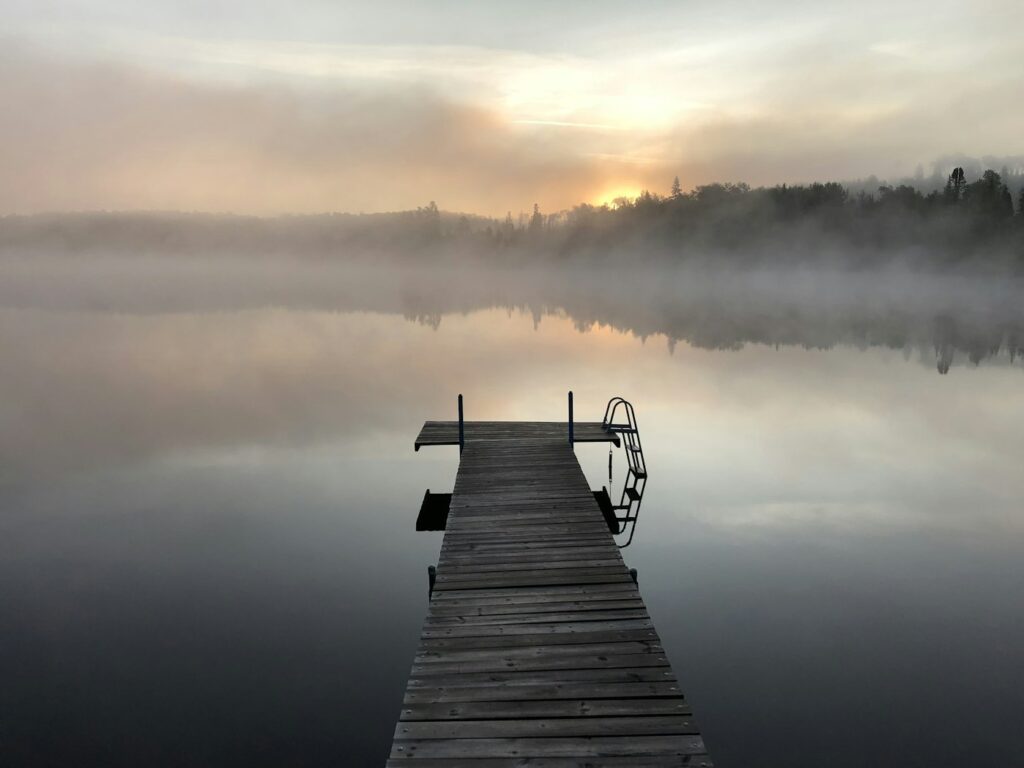A wooden dock reaching into a misty lake at dawn