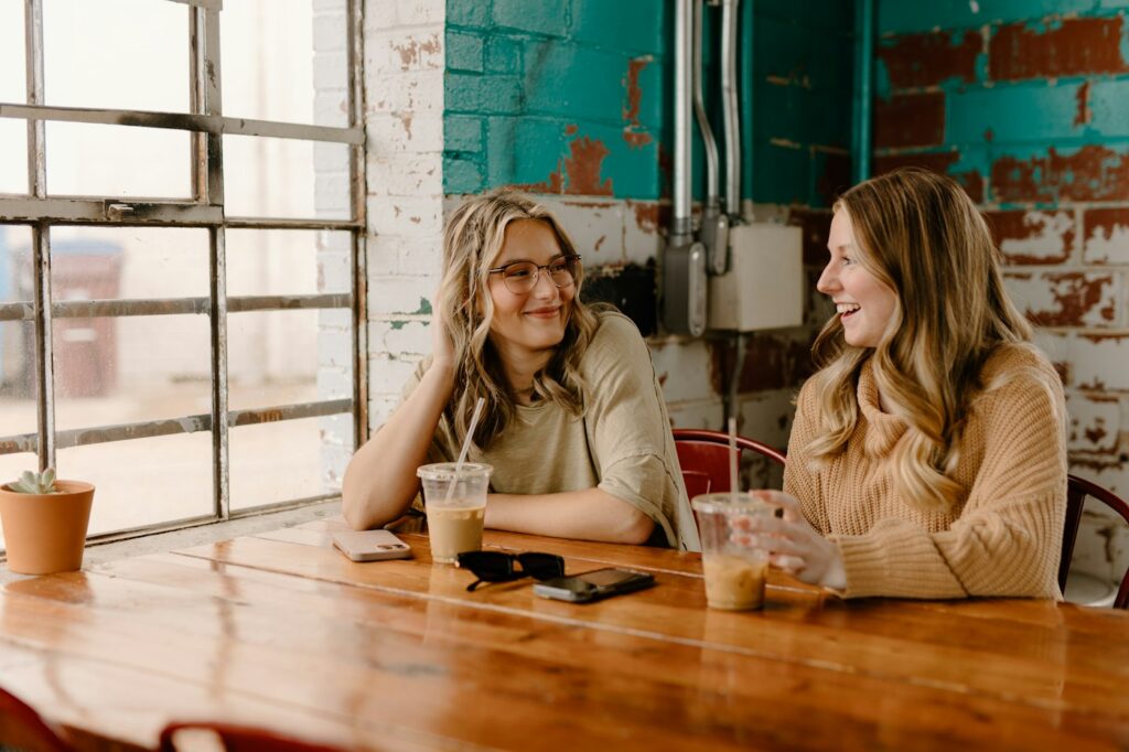 Two women talking at a wooden table